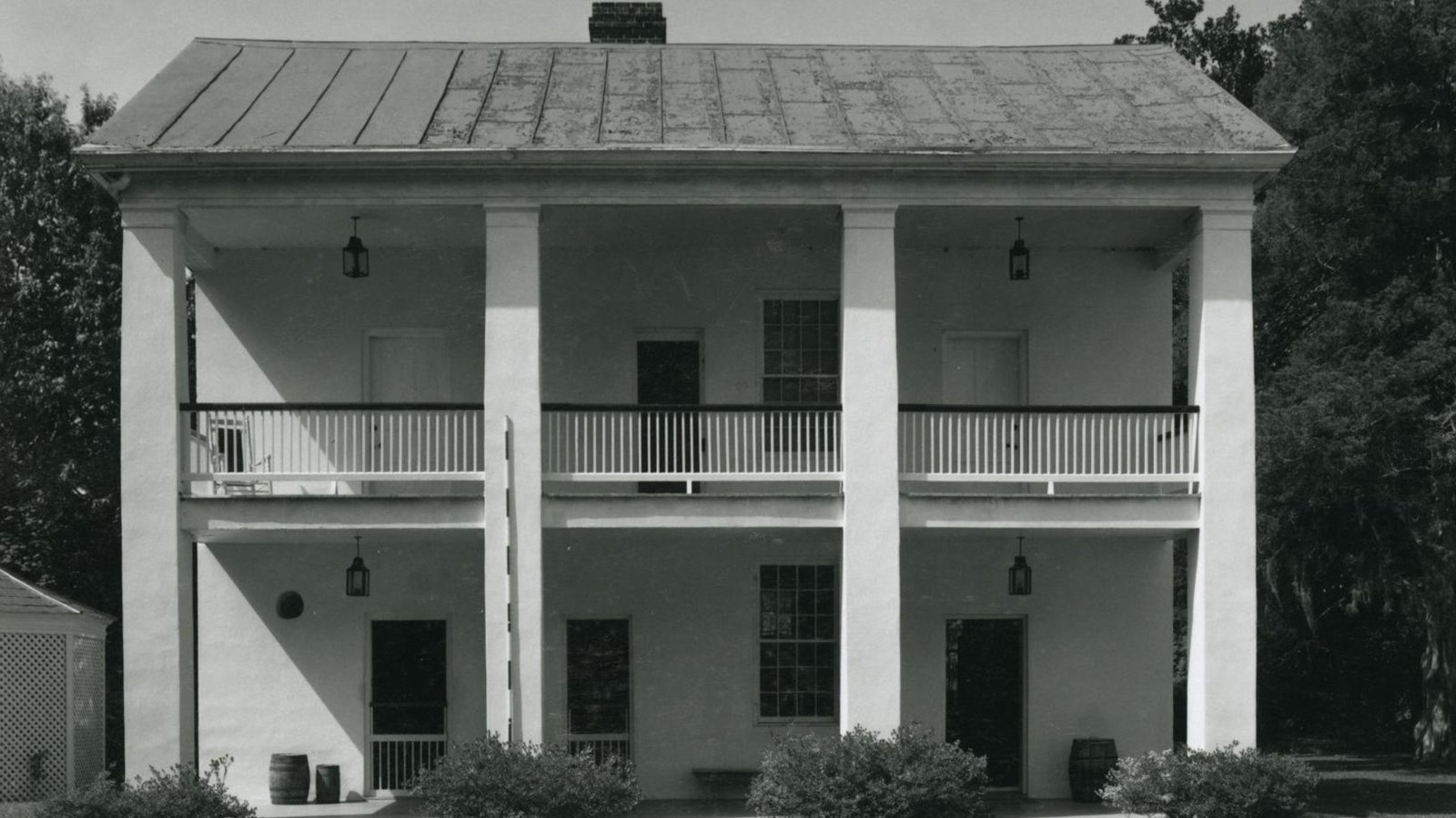 Two story brick building with four columns, first and first and second story porches