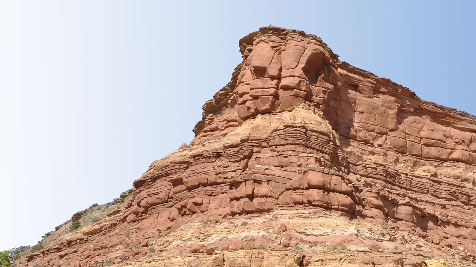 A large formation of orange sandstone rock resembling a long face. 