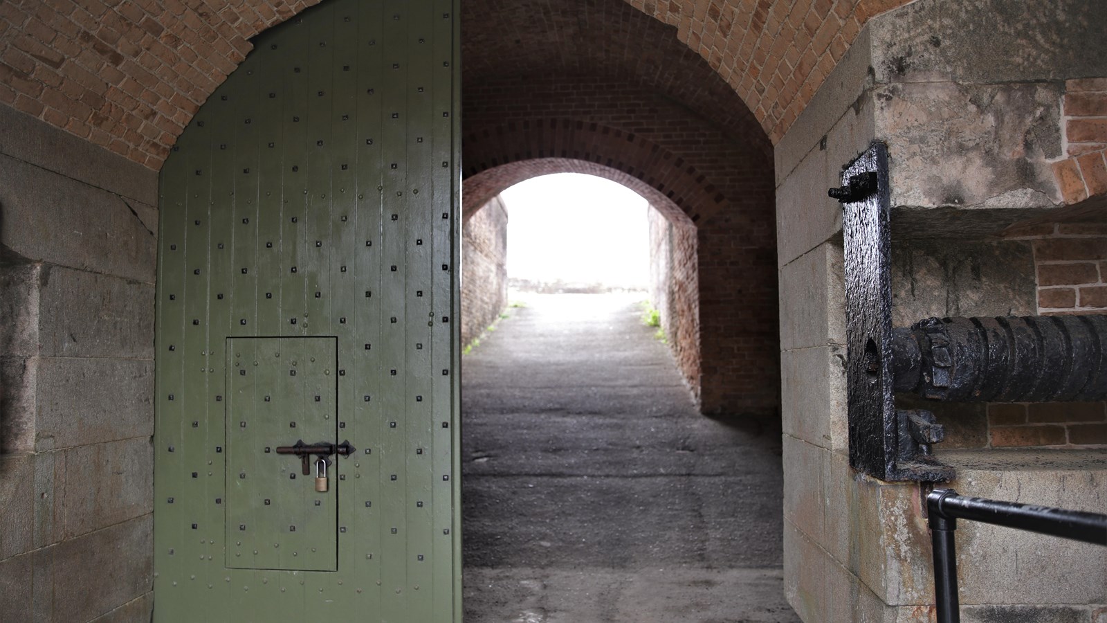 Two large, arched wooden doors stand at the front of a walkway.