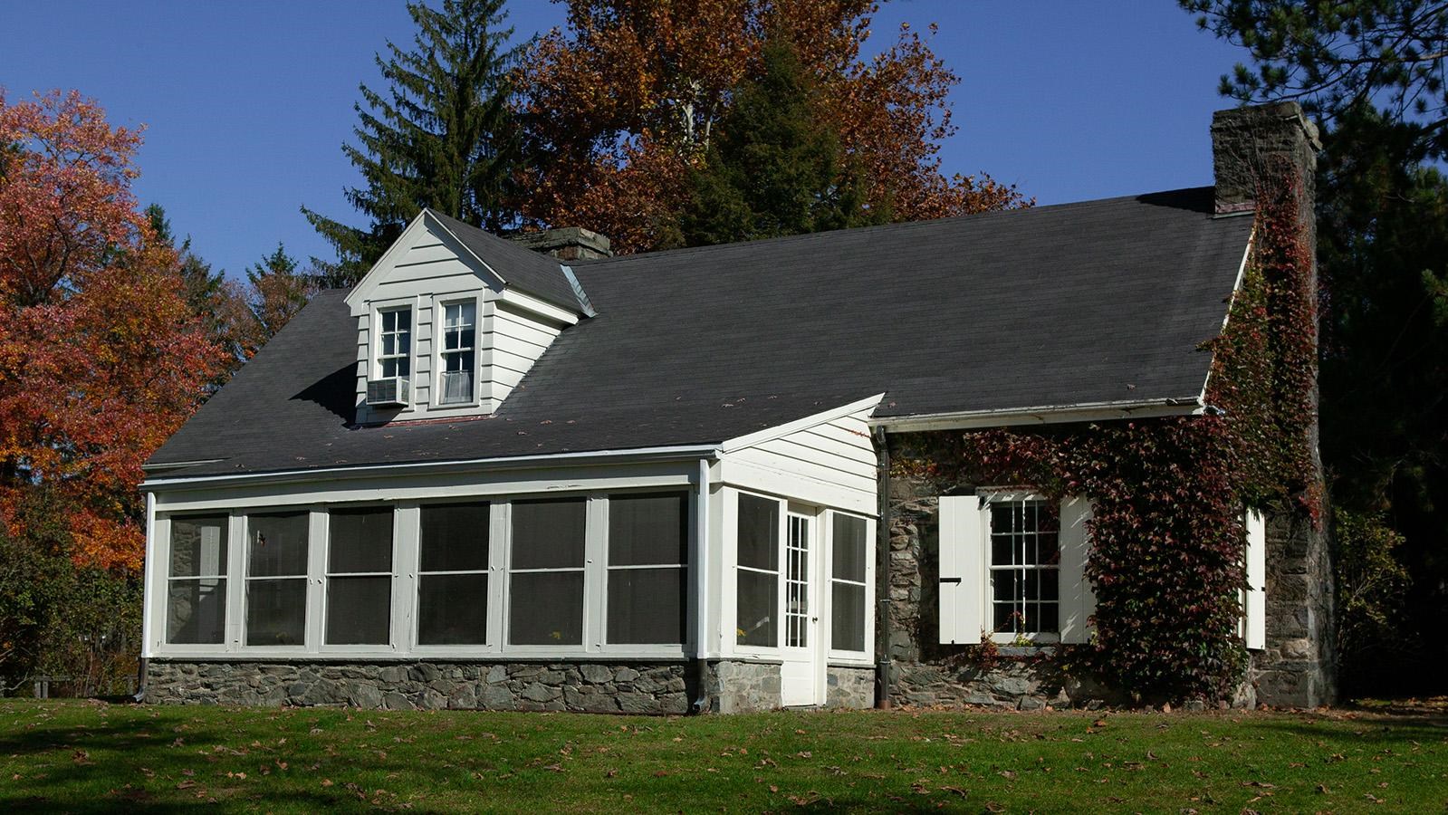 A one and a half story fieldstone cottage with screened porch.