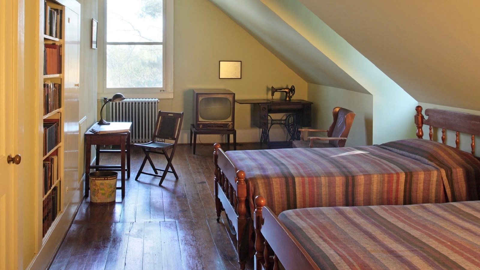 Margaret\'s room has two twin beds, a TV, sewing machine, and shelves lined with books