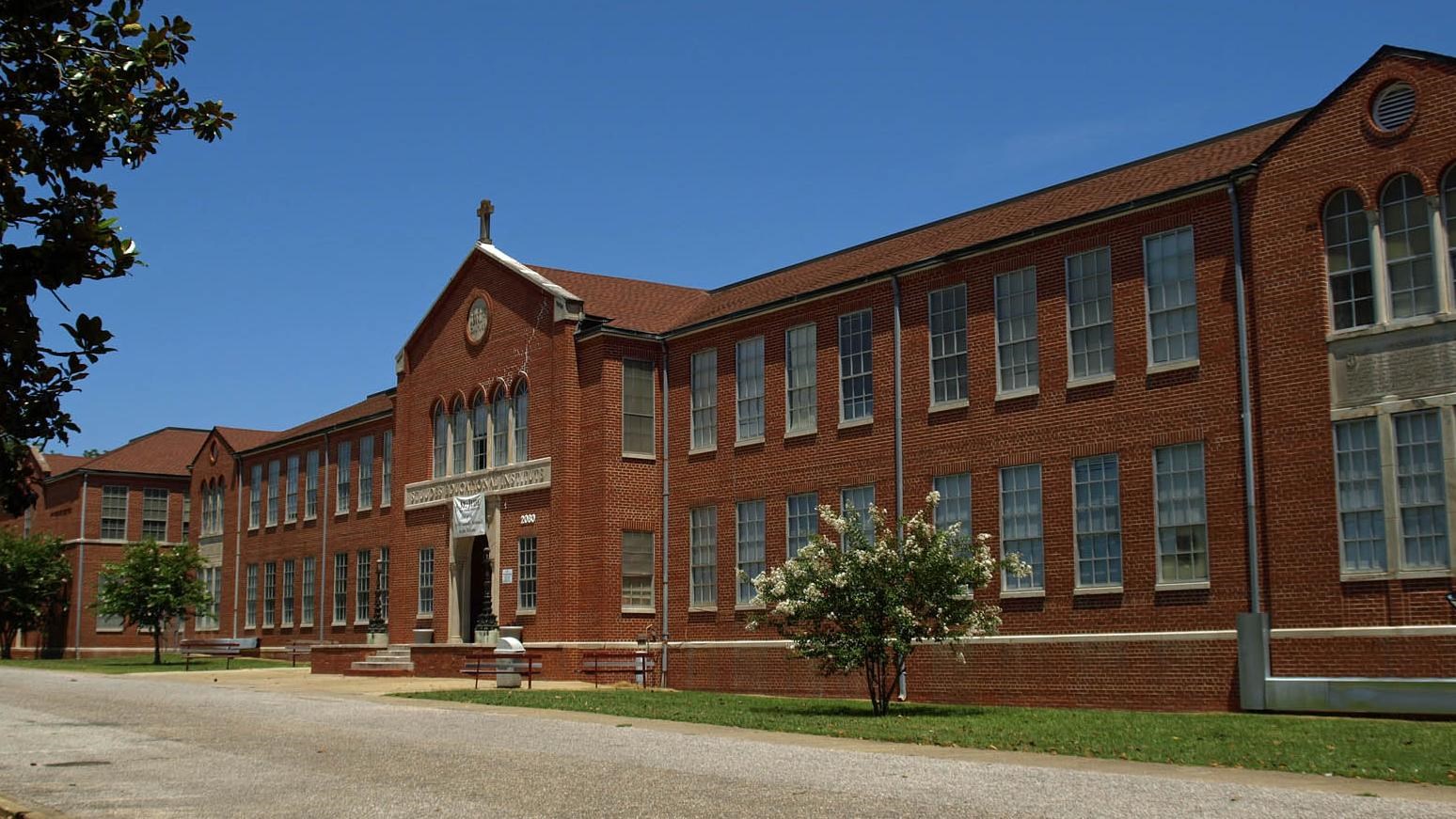 Long brick building with cross over entry way. Photo by Chris Pruitt CC BY-SA 3.0. 