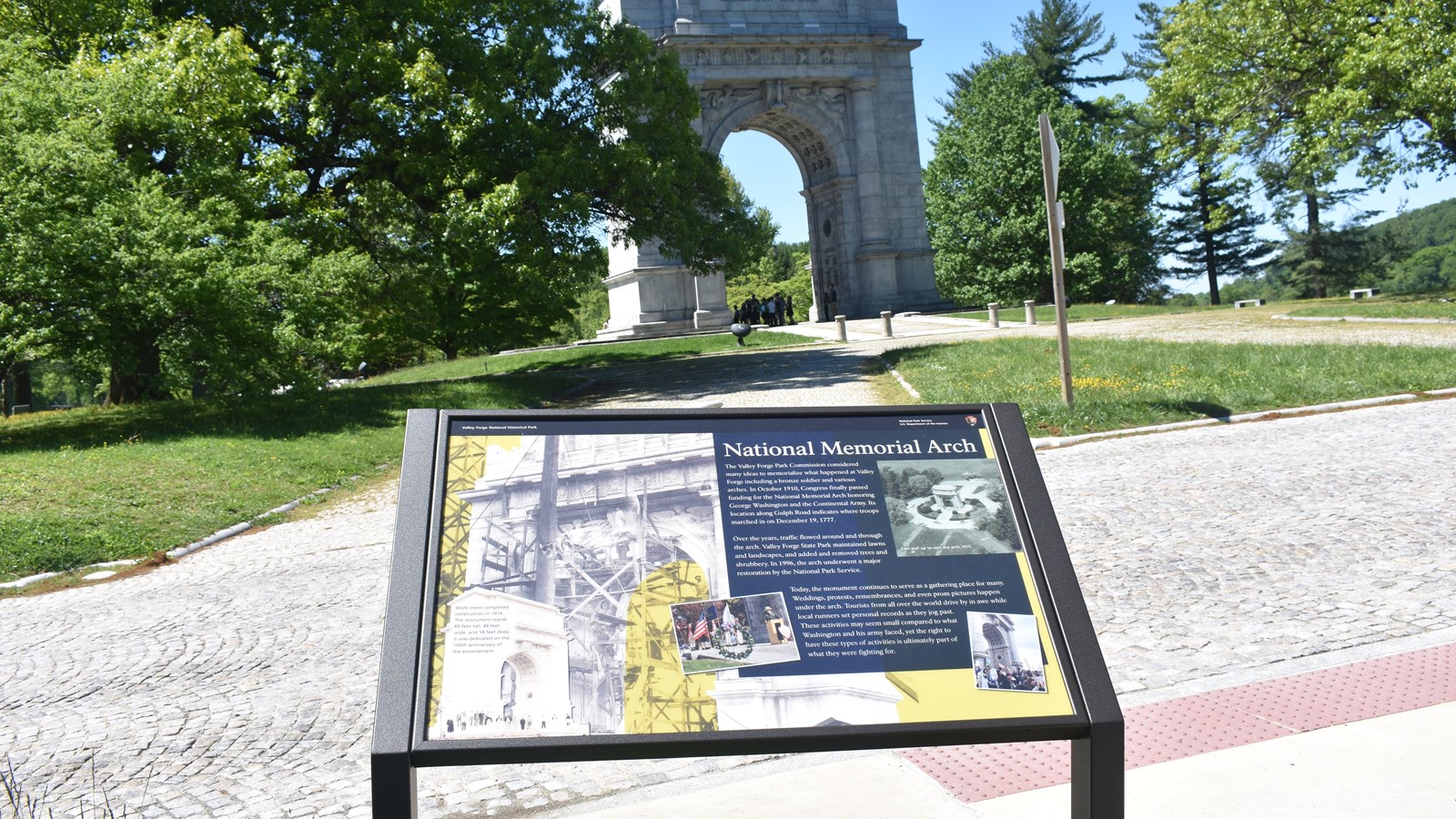 wayside exhibit panel showing historic photos of national memorial arch monument