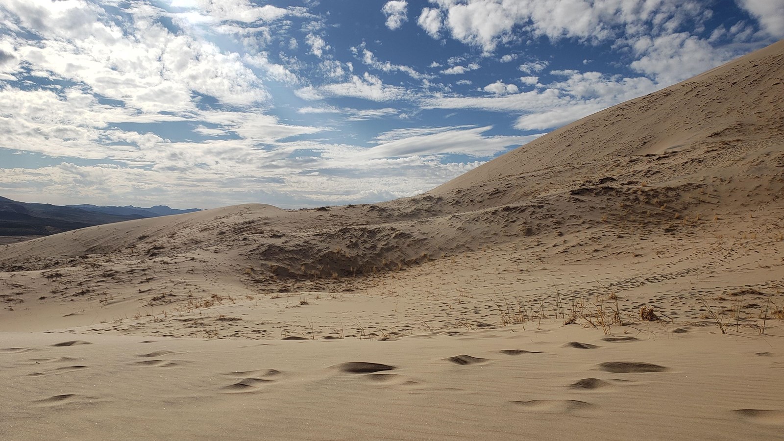 A cloudly blue sky above sand dunes 