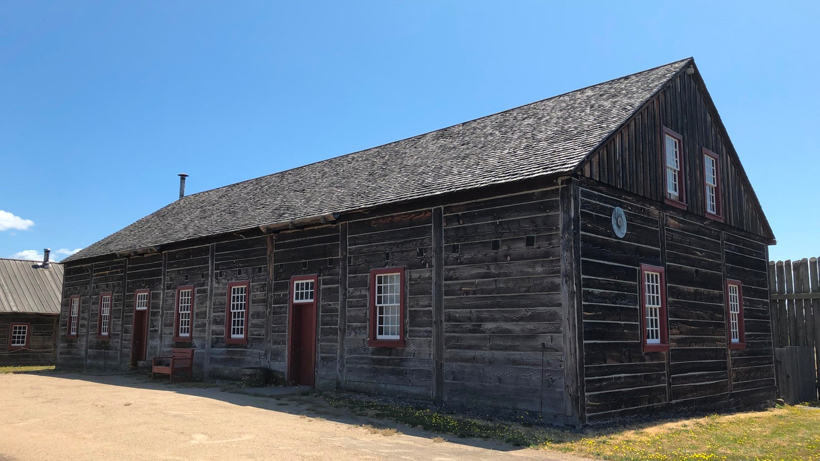 A long wooden building with two doors and several windows.