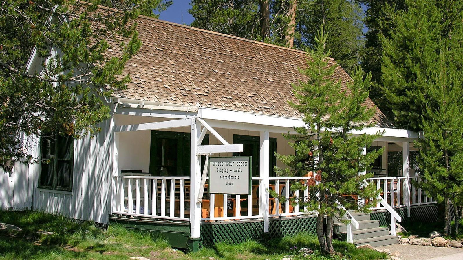 Wooden cabin painted white with a covered porch