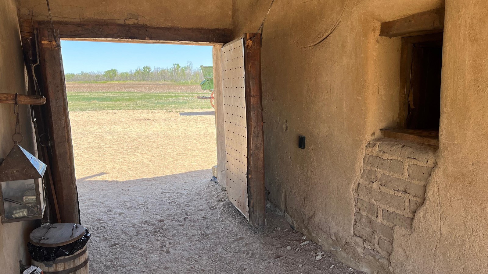 A gates entryway to an adobe fort with two sets of wooden double doors.