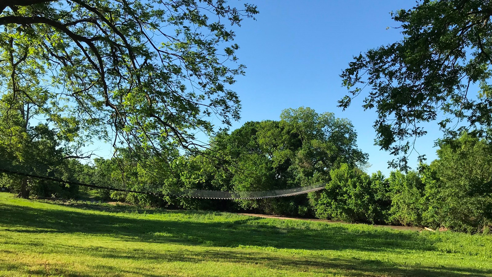 A large green grass field with a blue sky.