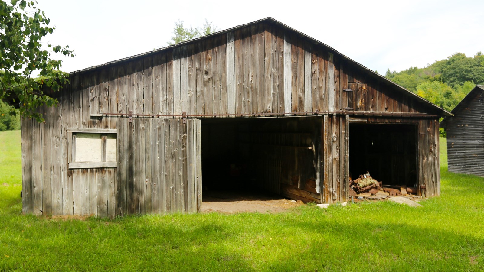 Vertical wood-sided building with two large open bays and a small window on the left