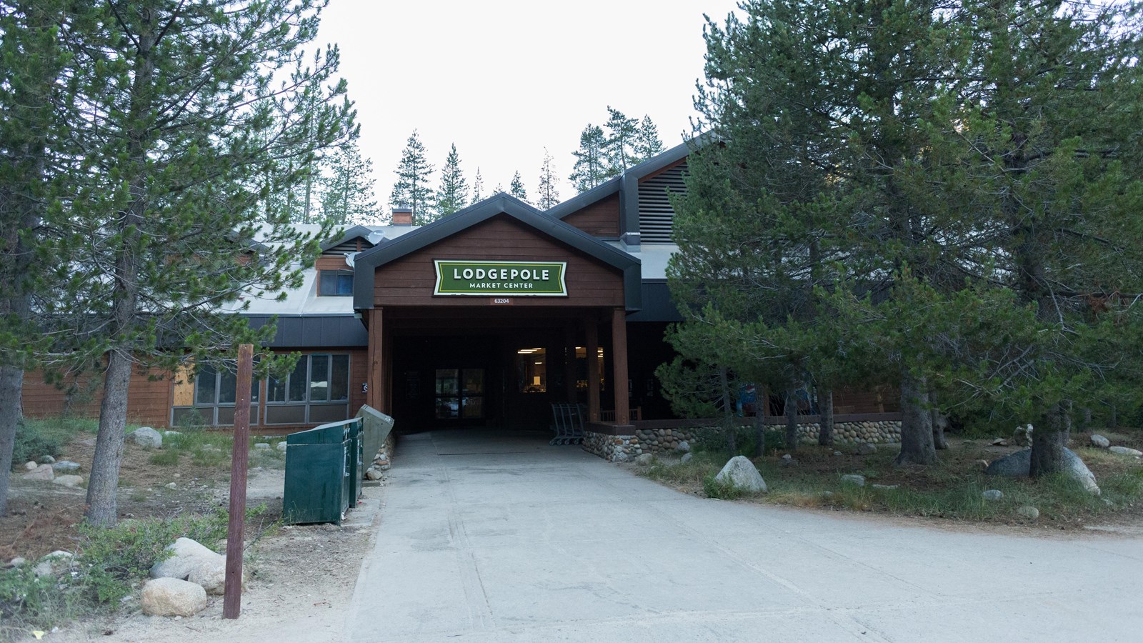 A cement path leads to a brown building with a green roof