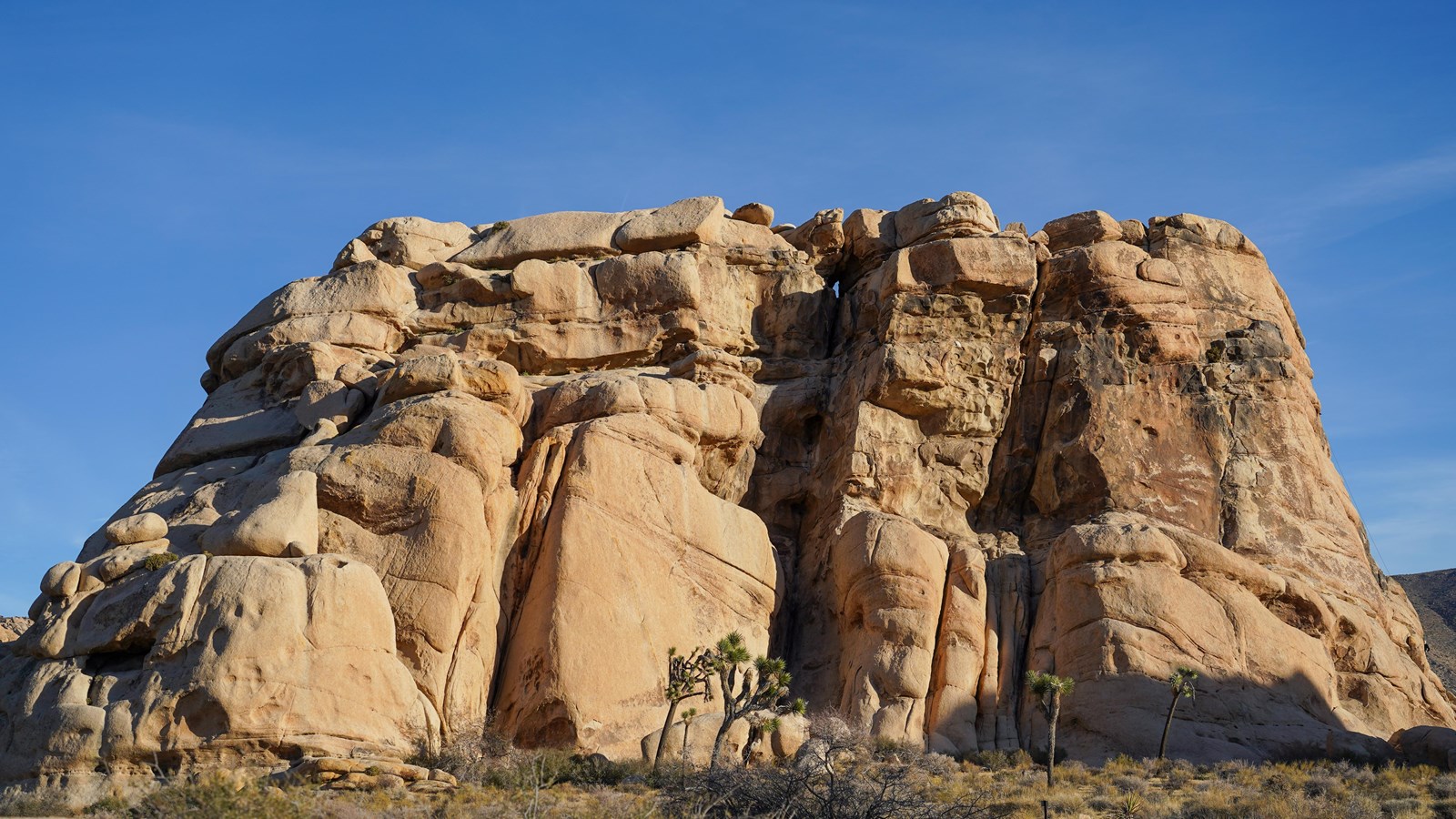 Large granite rock formation with many cracks and crevices.