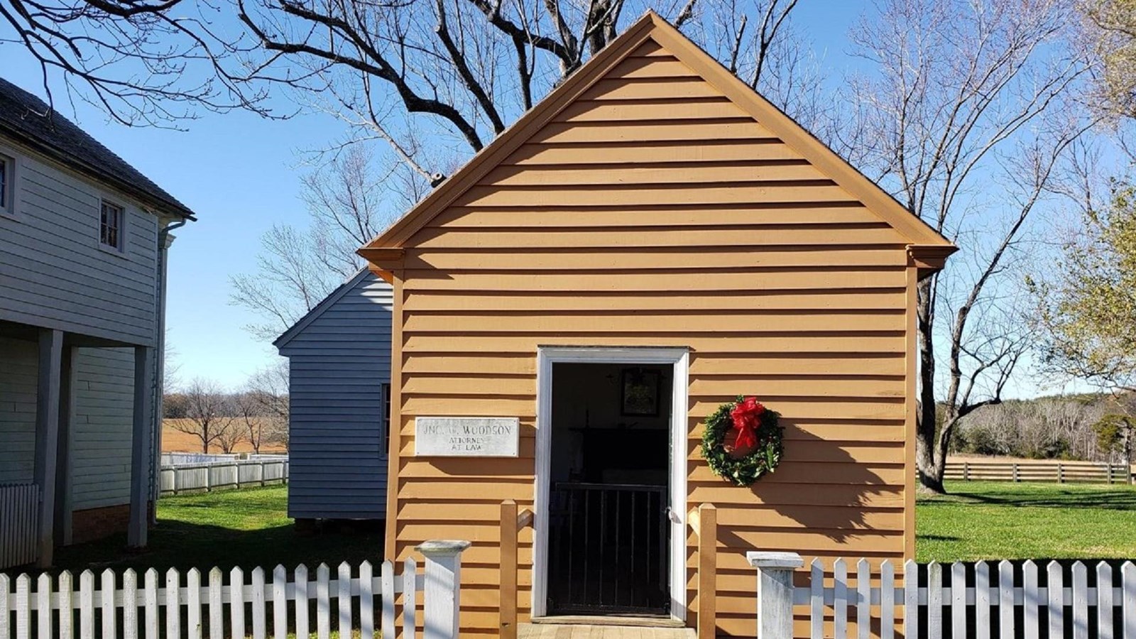 A small one-story wooden office painted a yellow/orange color.