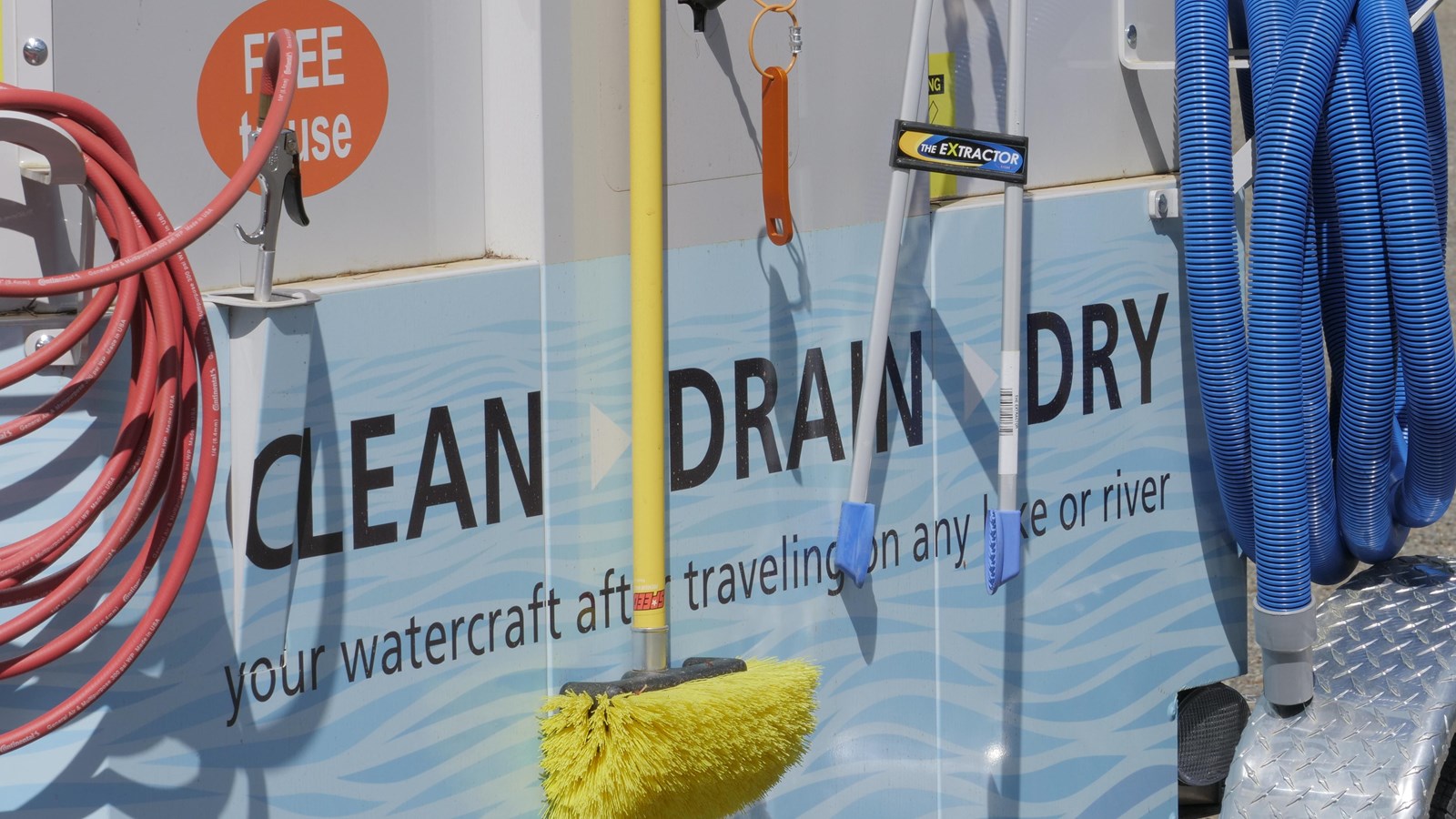 The side of a small trailer with hoses and brushes attached with the words 