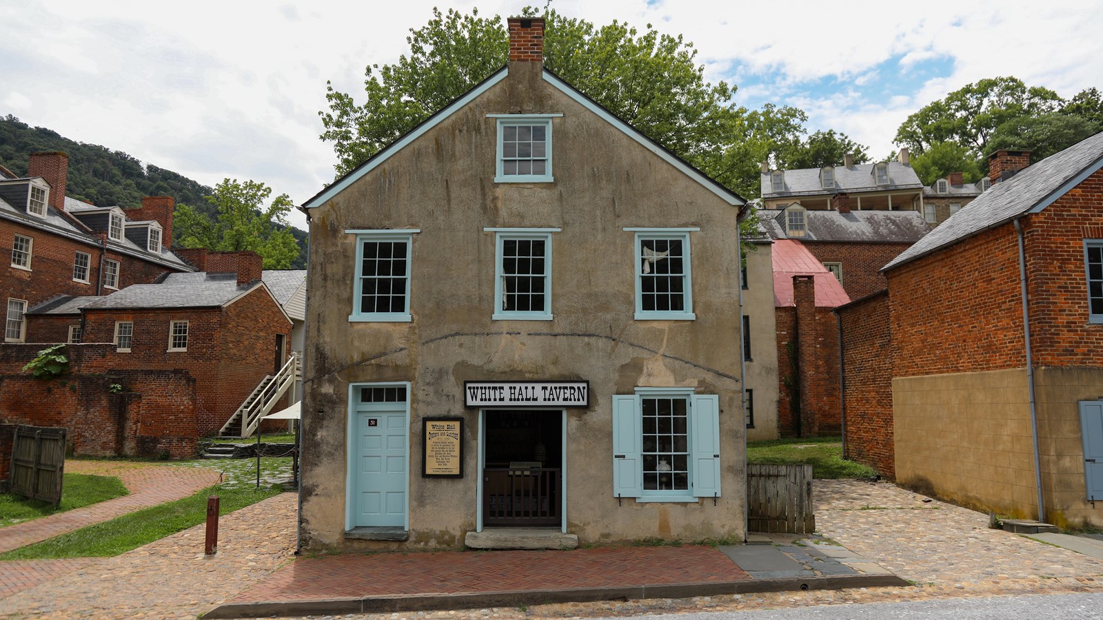 A stucco building stands in contrast to surrounding brick buildings.