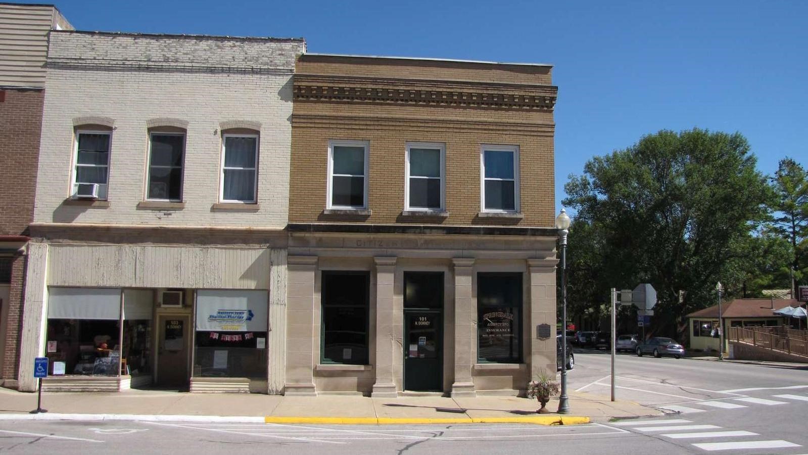 A bank building has limestone pilasters below a brick-faced second story.