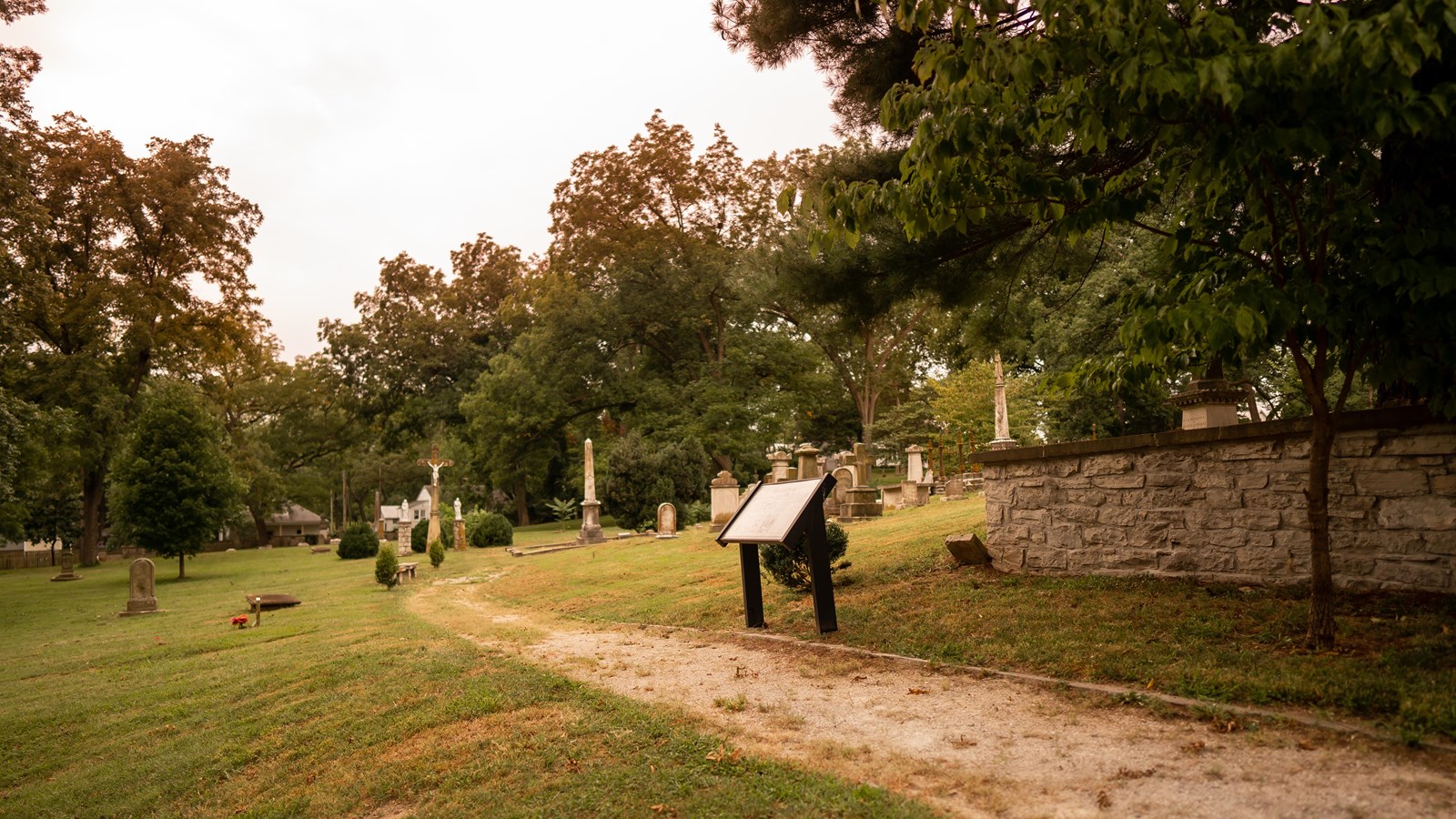 Hundreds of stone tombstones scatter the hilly terrain with a fence on the outside perimeter. 