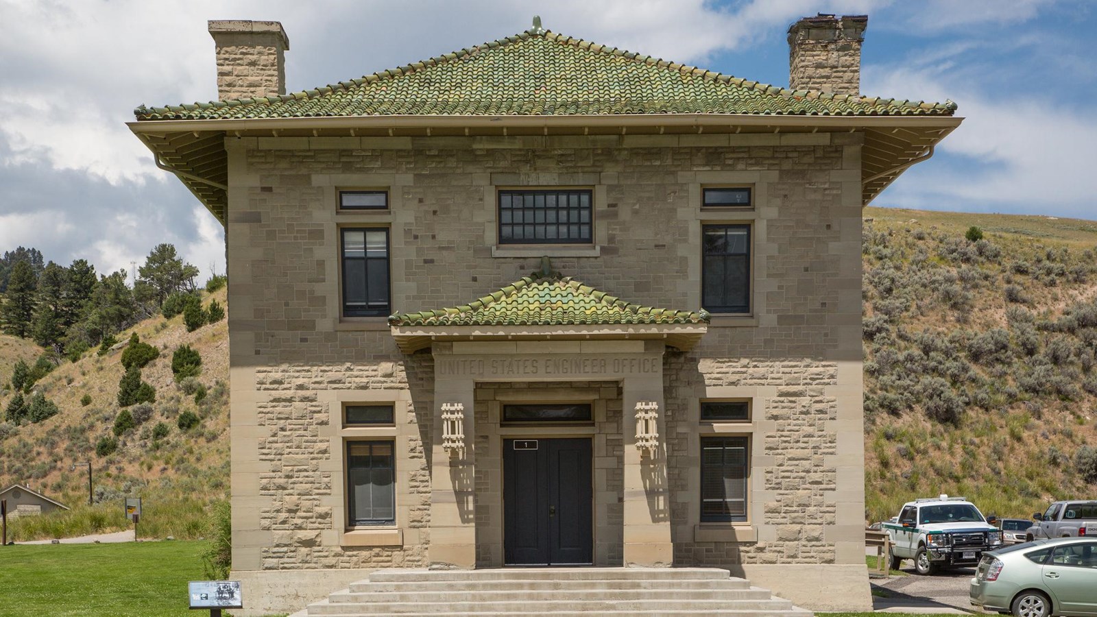 A historic stone building with a green shingled roof.