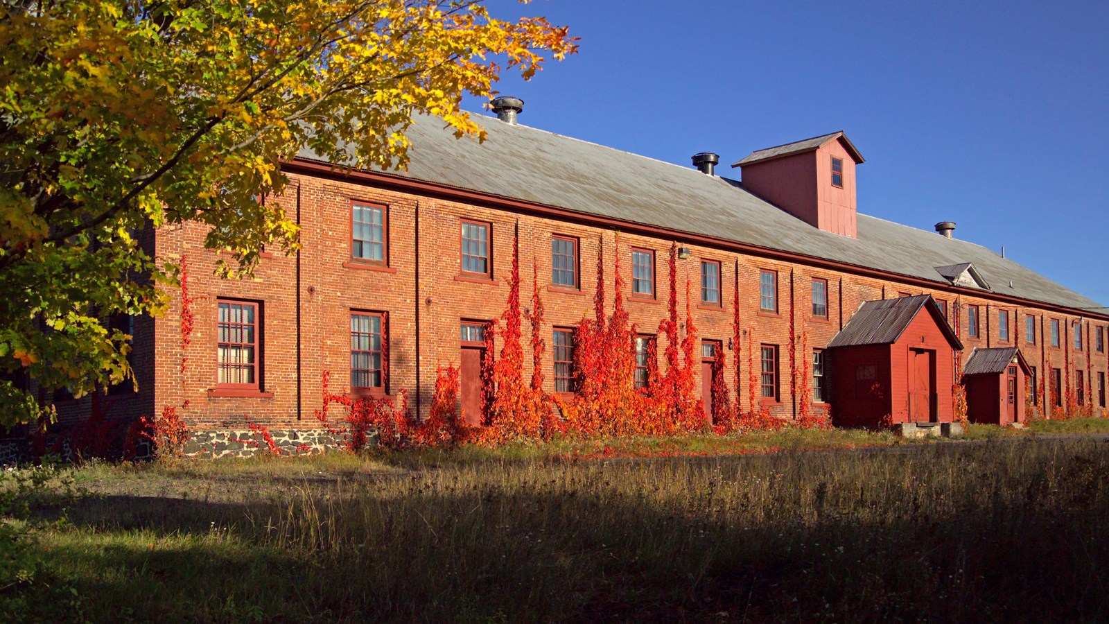 Fall scene with the sun illuminating a long 2 story red brick warehouse