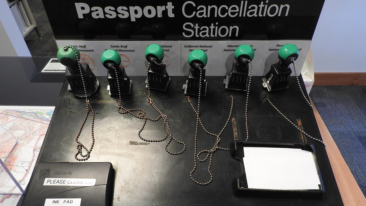 Six passport stamps are chained to a pedestal.