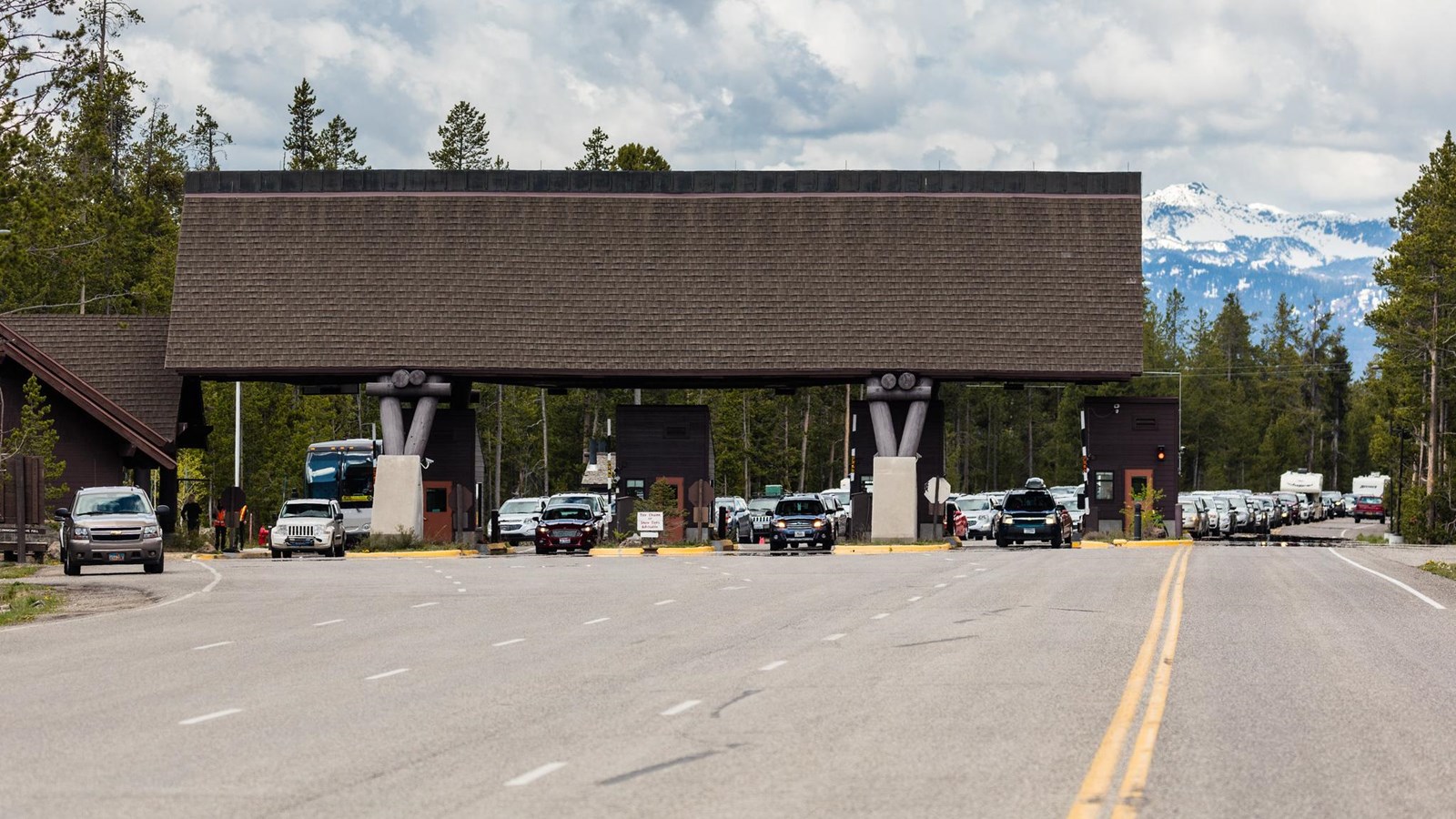 Four lanes of vehicles wait to travel through a modern entrance station.