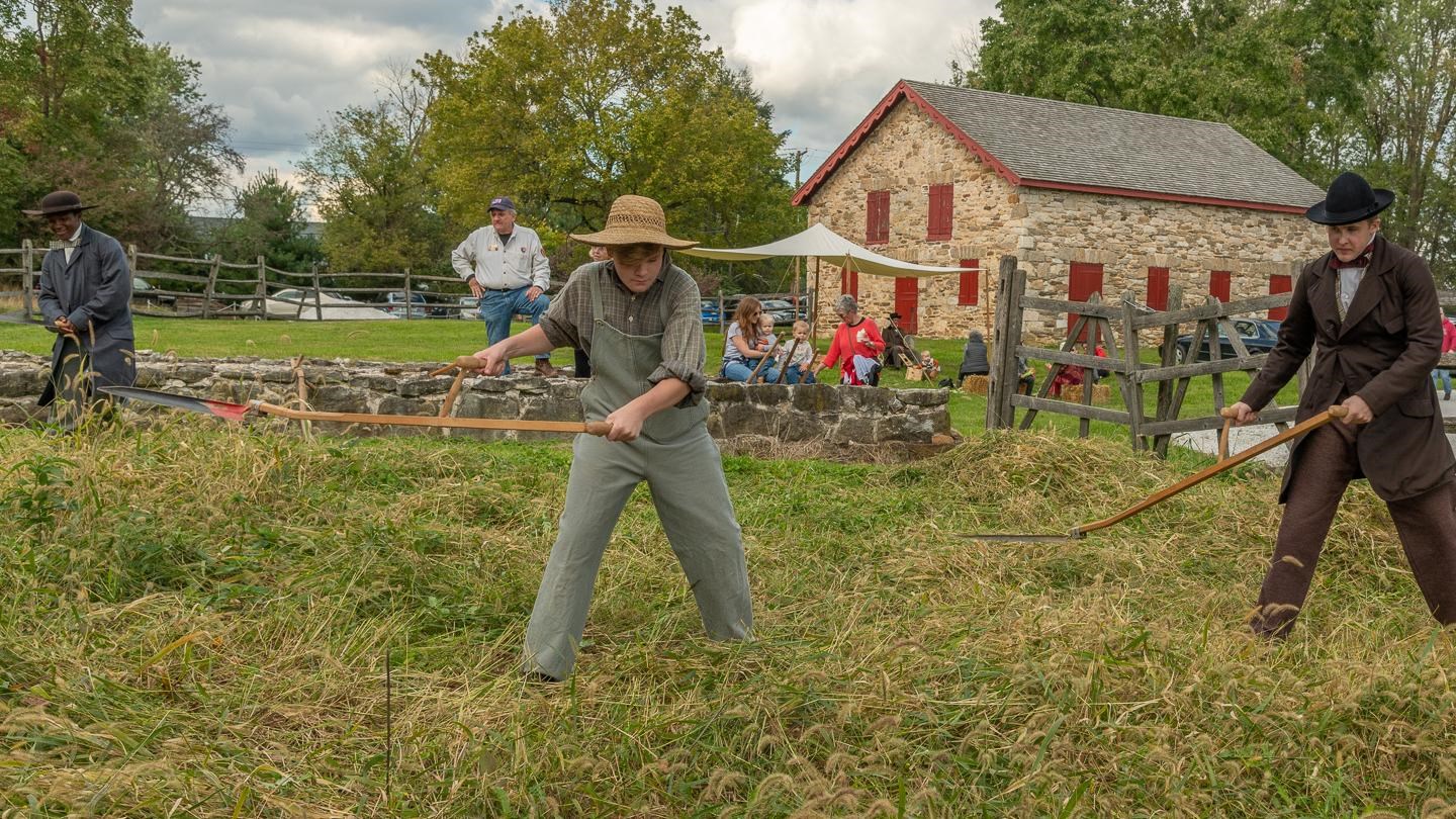 Living historians working in a field. The corn crib foundations are behind them.