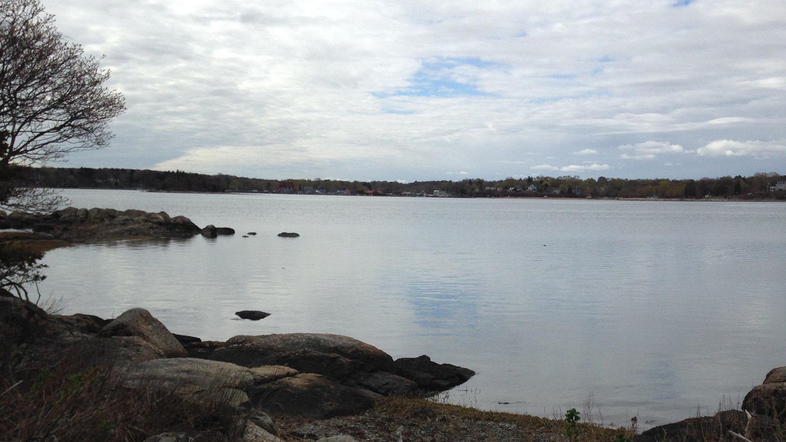 Outlook of a rocky beach looking out on the water, there is land in the distance