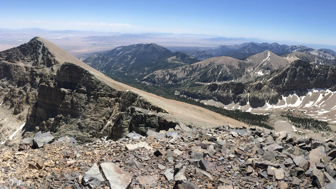 View from wheeler peak with blue skies and rocky mountain peaks.
