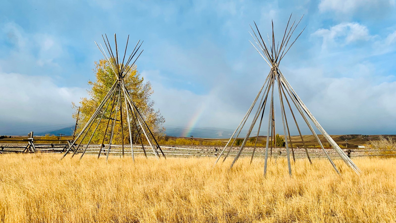 A pair of lodge pole tipi frames sitting on display in the grass at Grant-Kohrs Ranch.
