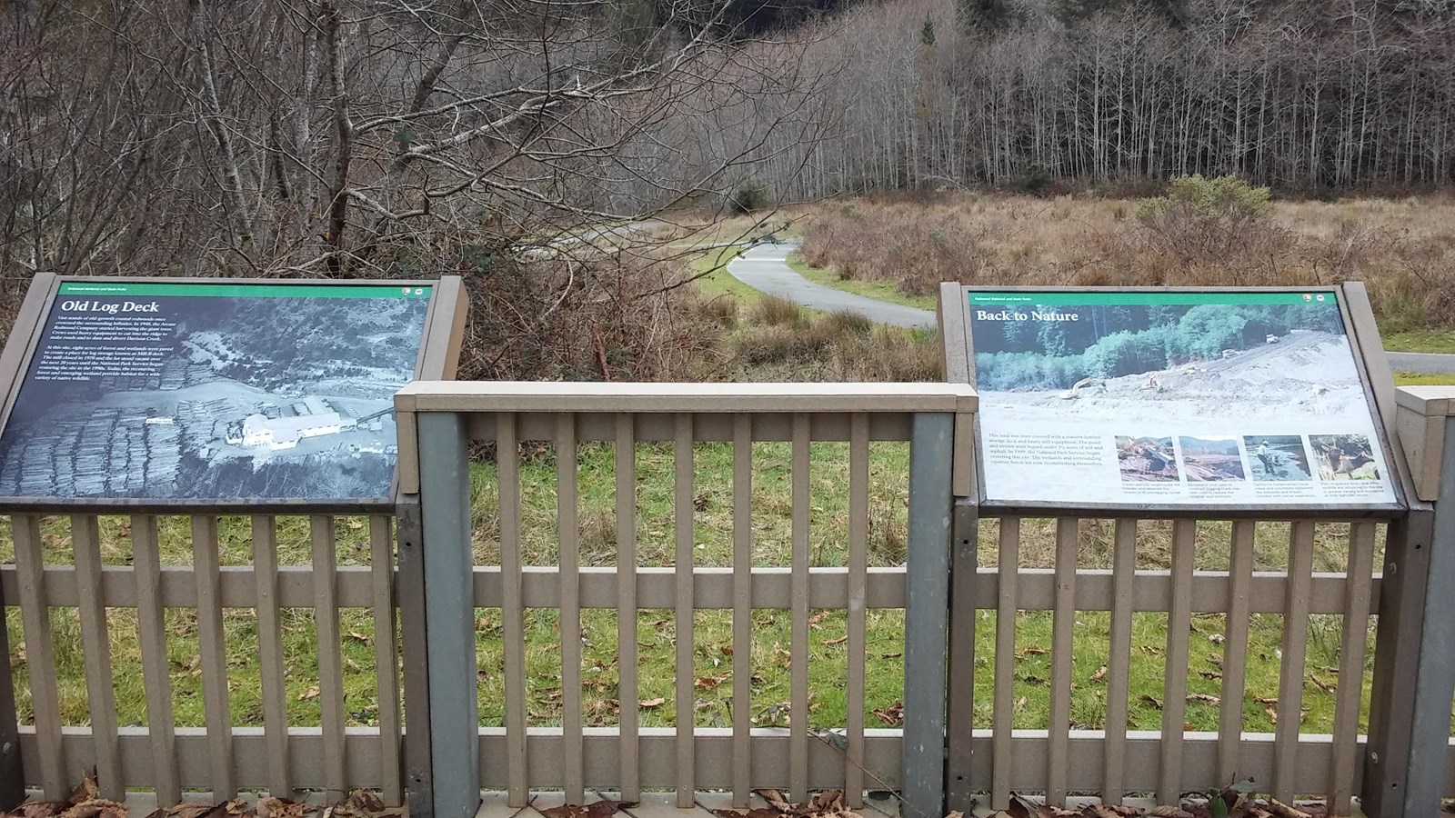 Two interpretive panels and views of meadow and a paved trail.
