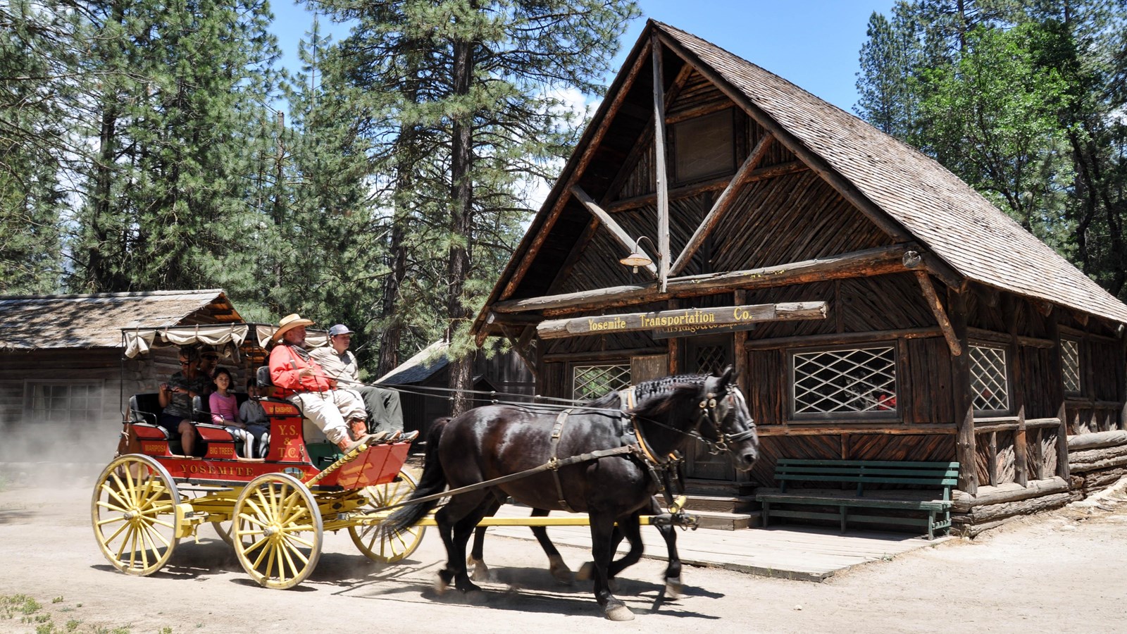 Wooden transportation office building with horse drawn stage and passengers in foreground