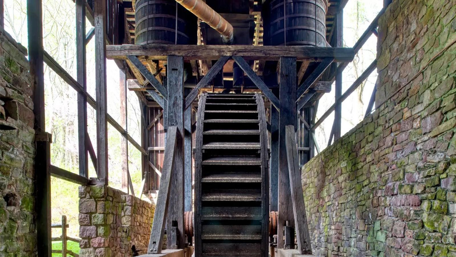 A large, wooden waterwheel surrounded by a stone wall. 