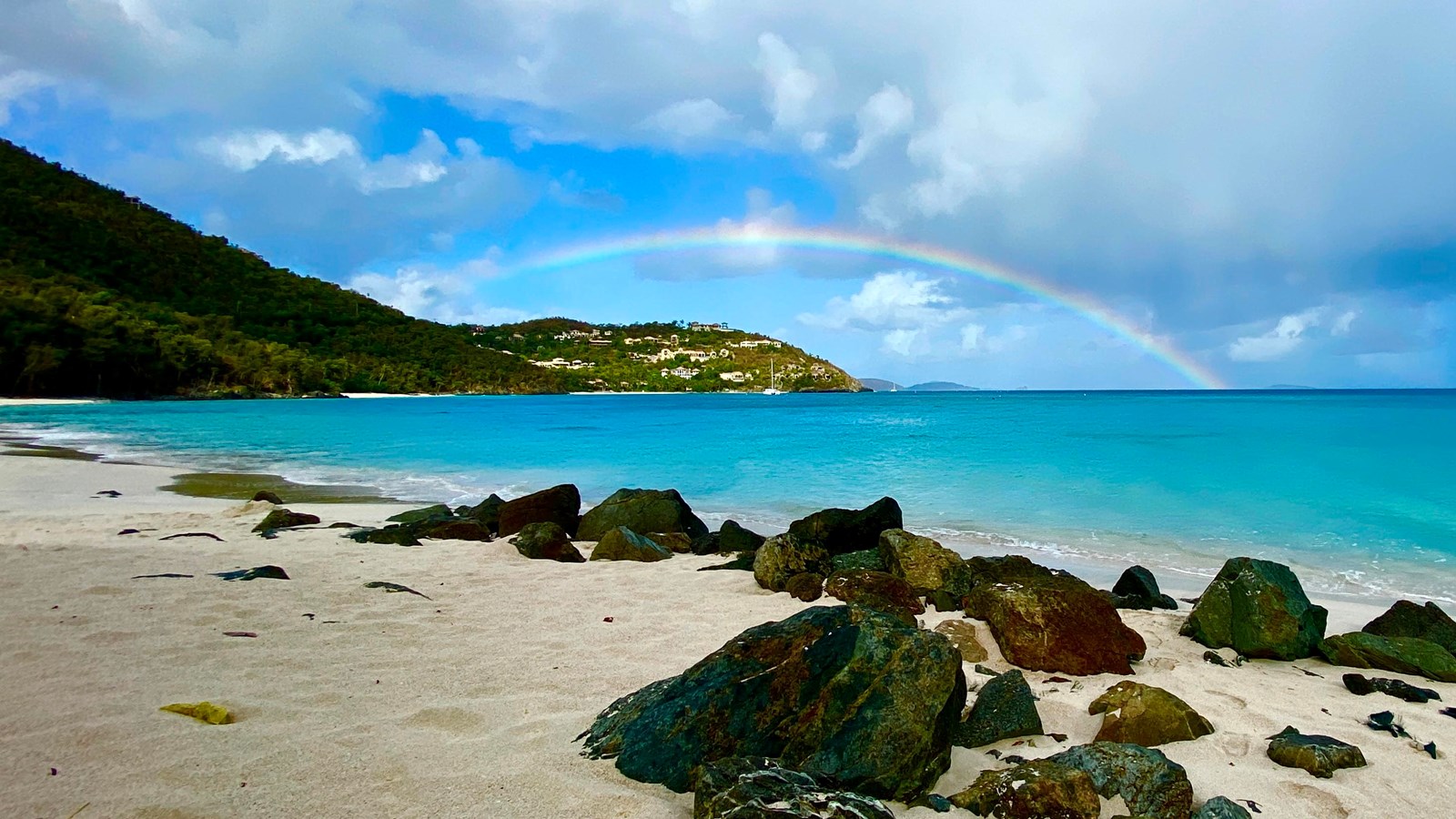 Black rocks along the beach provide contrast to the white sand at Cinnamon Bay.