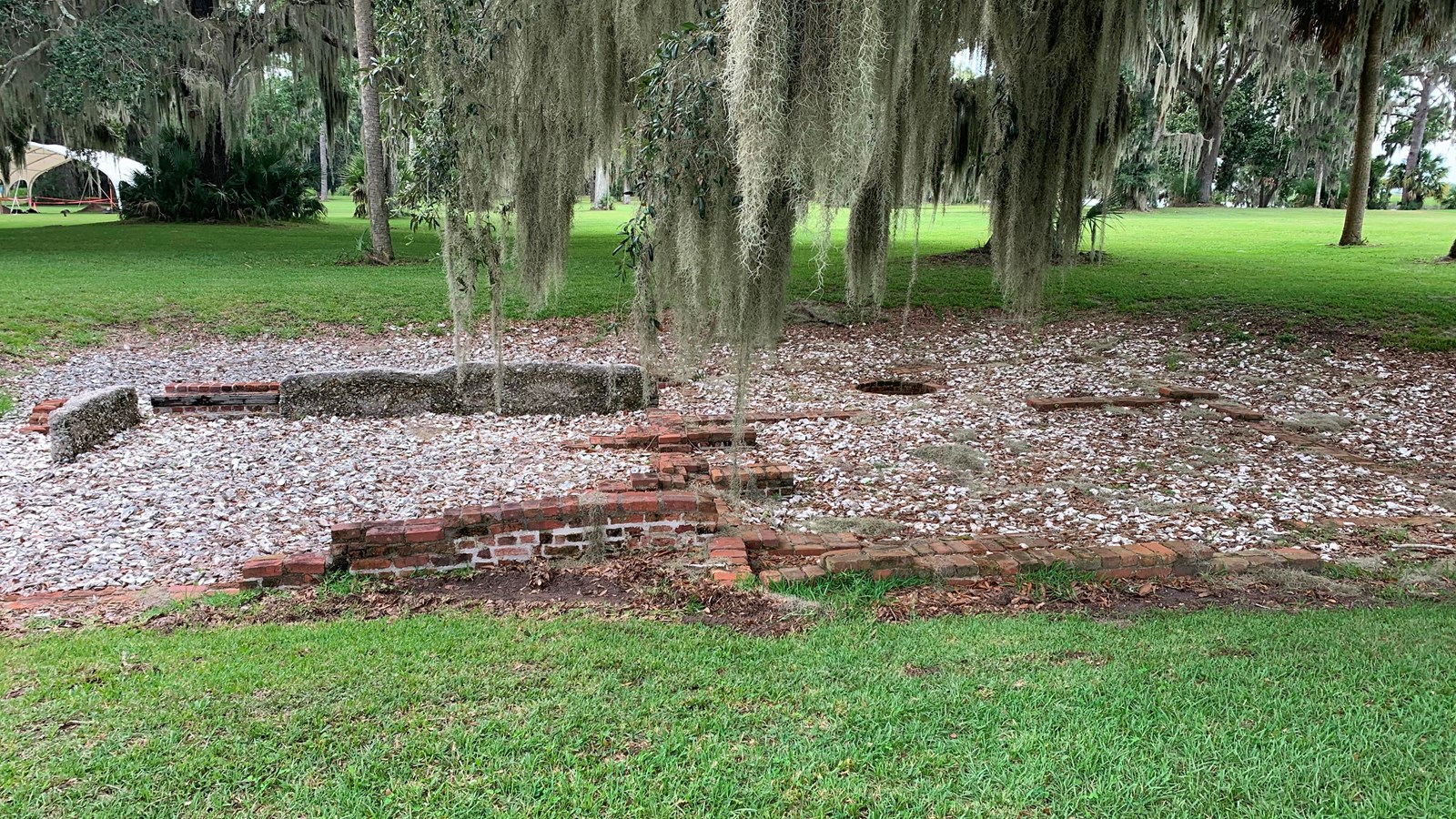 Shallow brick and tabby foundation with oyster shells in the floor space. Grass surrounds the duple.