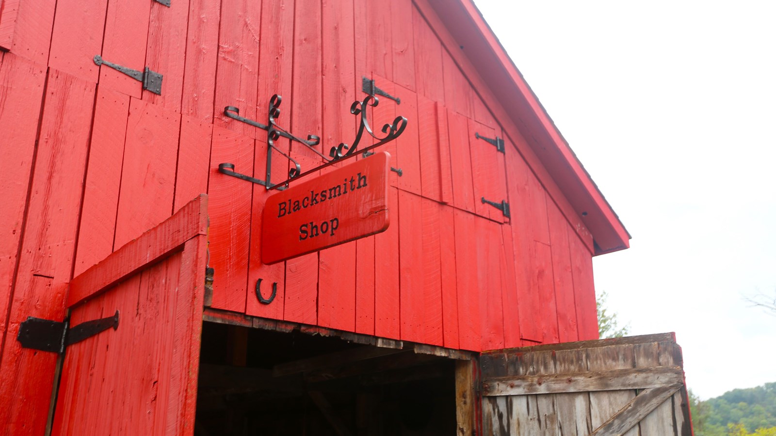 Close up of red-painted wooden building with red sign with black lettered 