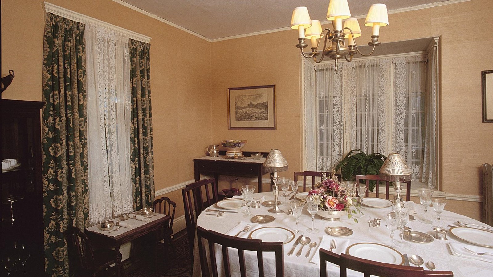 Dining room with dining table with tablecloth and six place settings. Children\'s table for two.