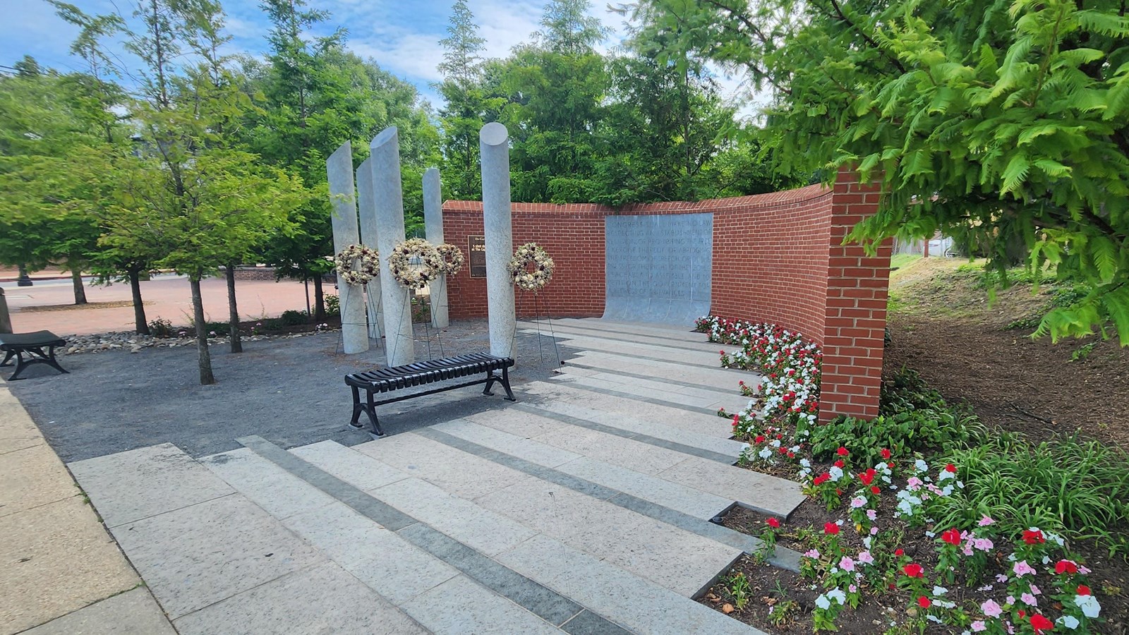 A park with a small brick wall and some pillars.