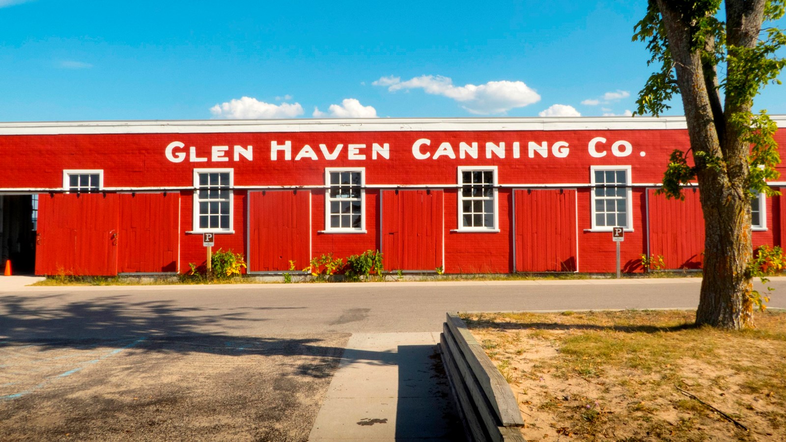 Bright red, low building with four white trimmed windows and white block letters