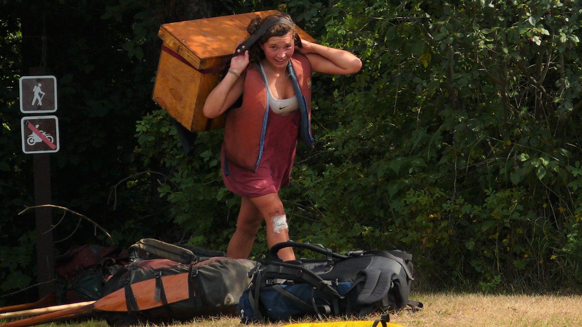 A person carrying a large box held in place with a head strap.