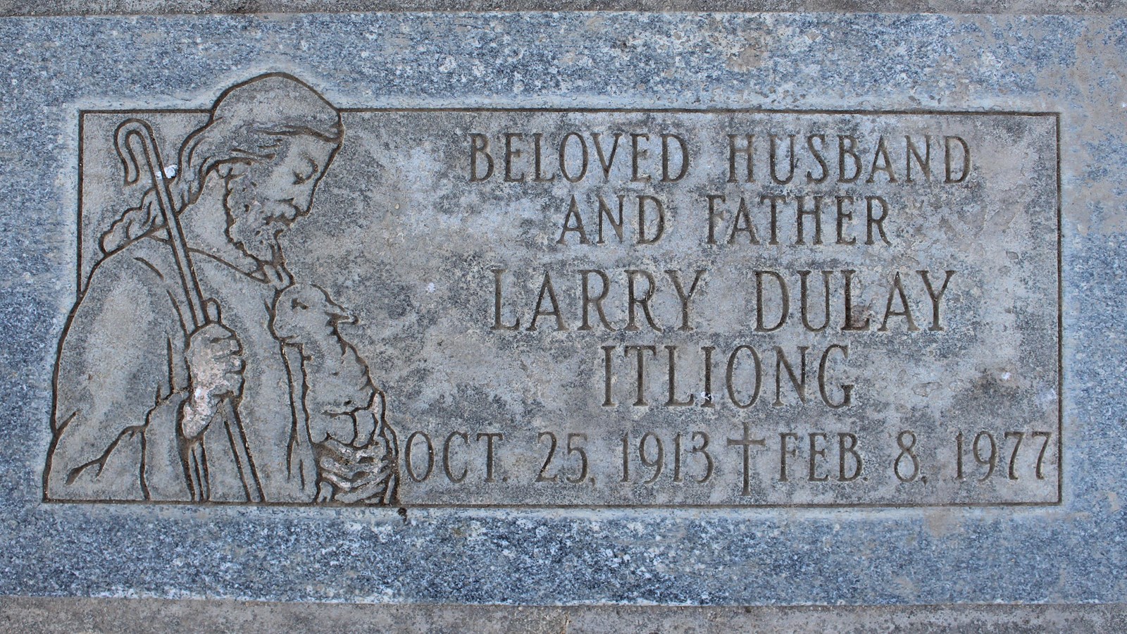 A gray gravestone for Larry Dulay Itliong features an image of Jesus cradling a lamb.