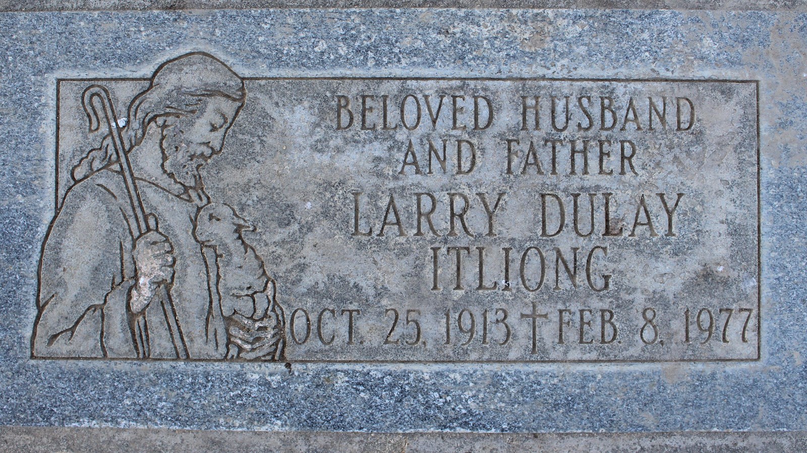 A gray gravestone for Larry Dulay Itliong features an image of Jesus cradling a lamb.