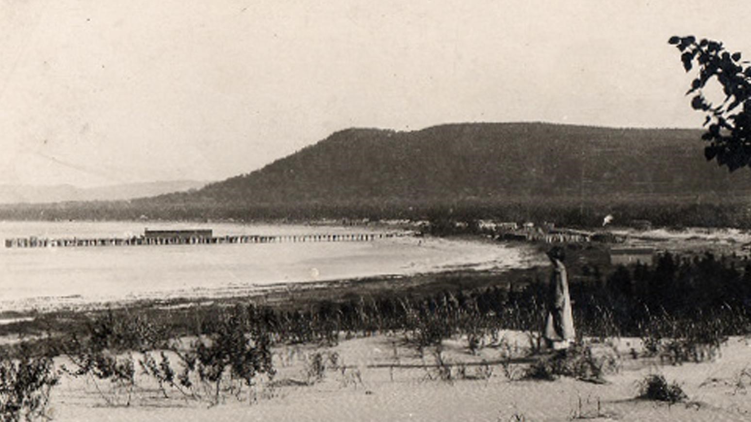 Historic photo of wooden dock and piers reaching from the beach out into a large bay