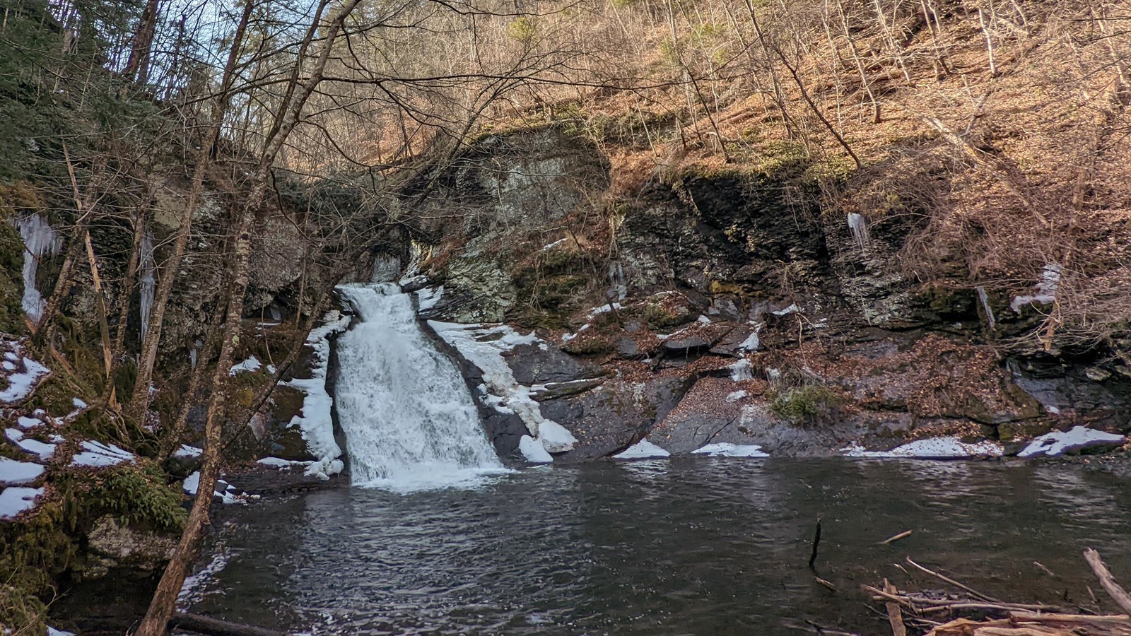 A small waterfall surrounded by rocks and bare trees.