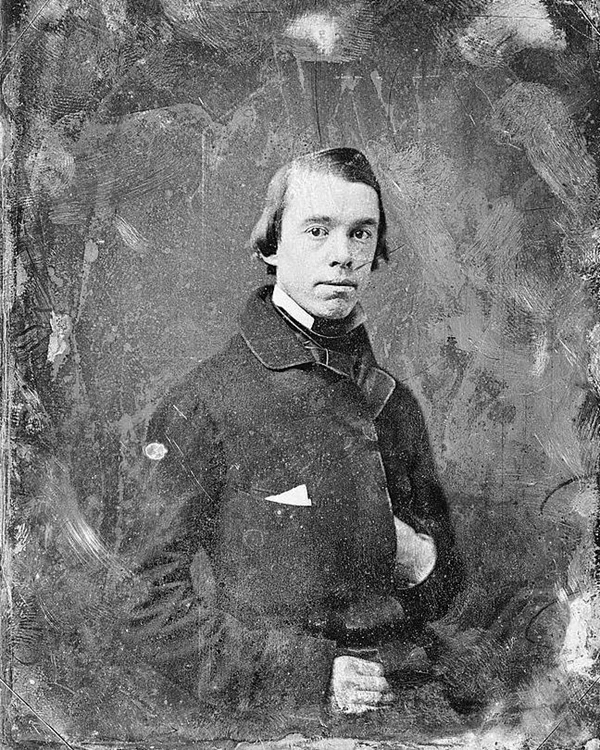 Young man dressed in 1800s clothing with one hand in coat.