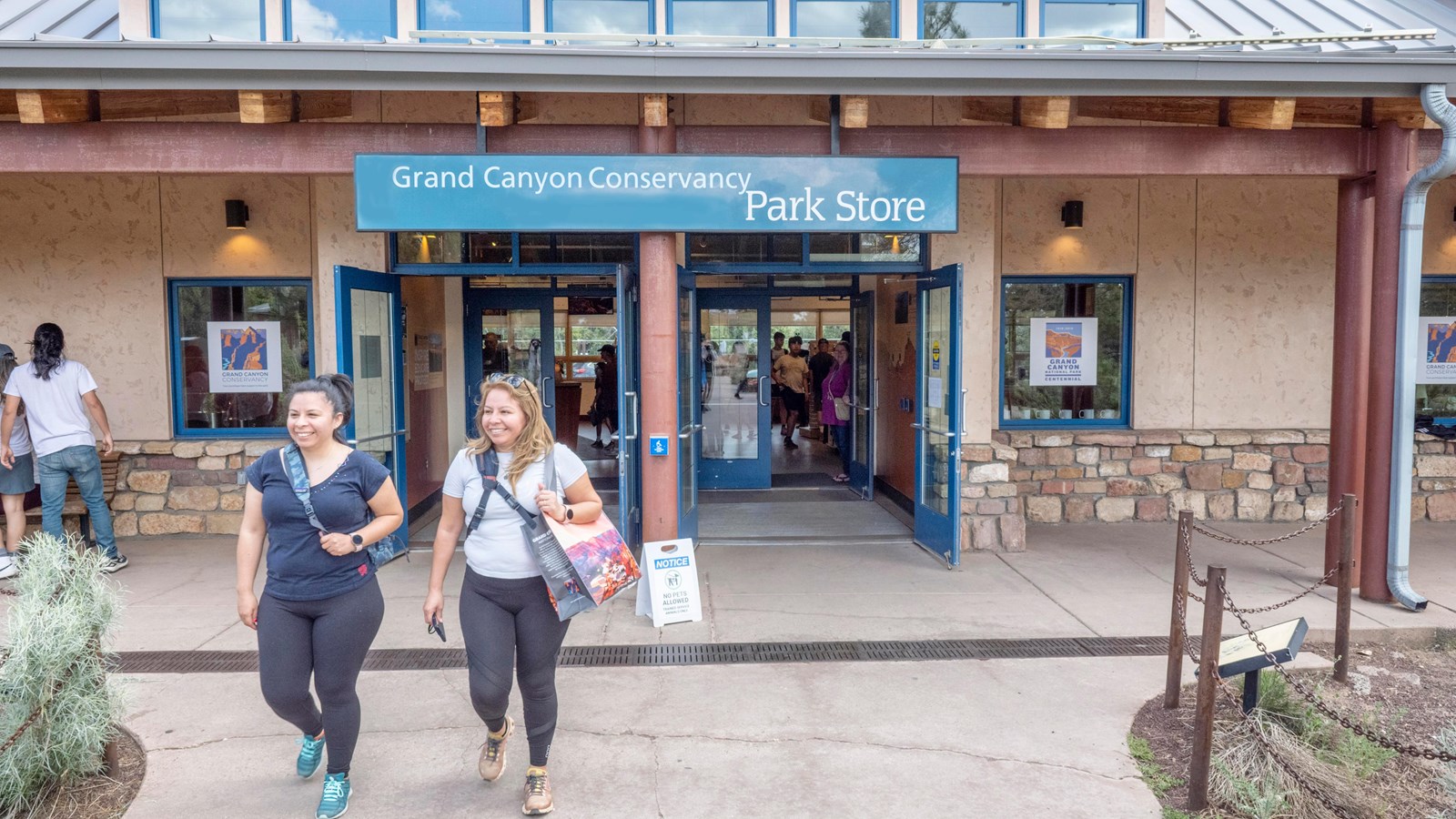 Two people walk out of a storefront; sign above them reads 