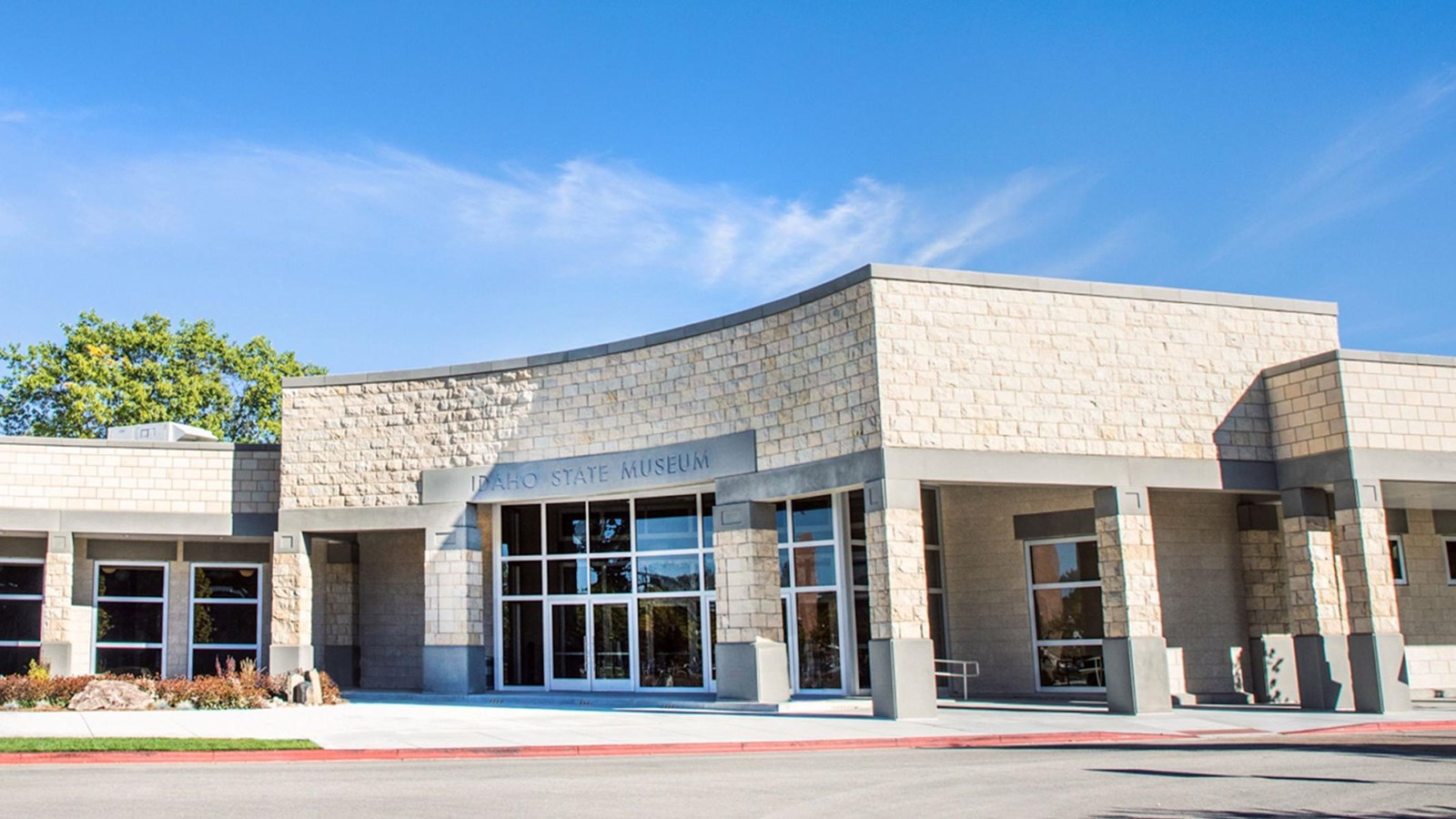 Single story, modern white and gray stone building with tinted windows around the front of the build
