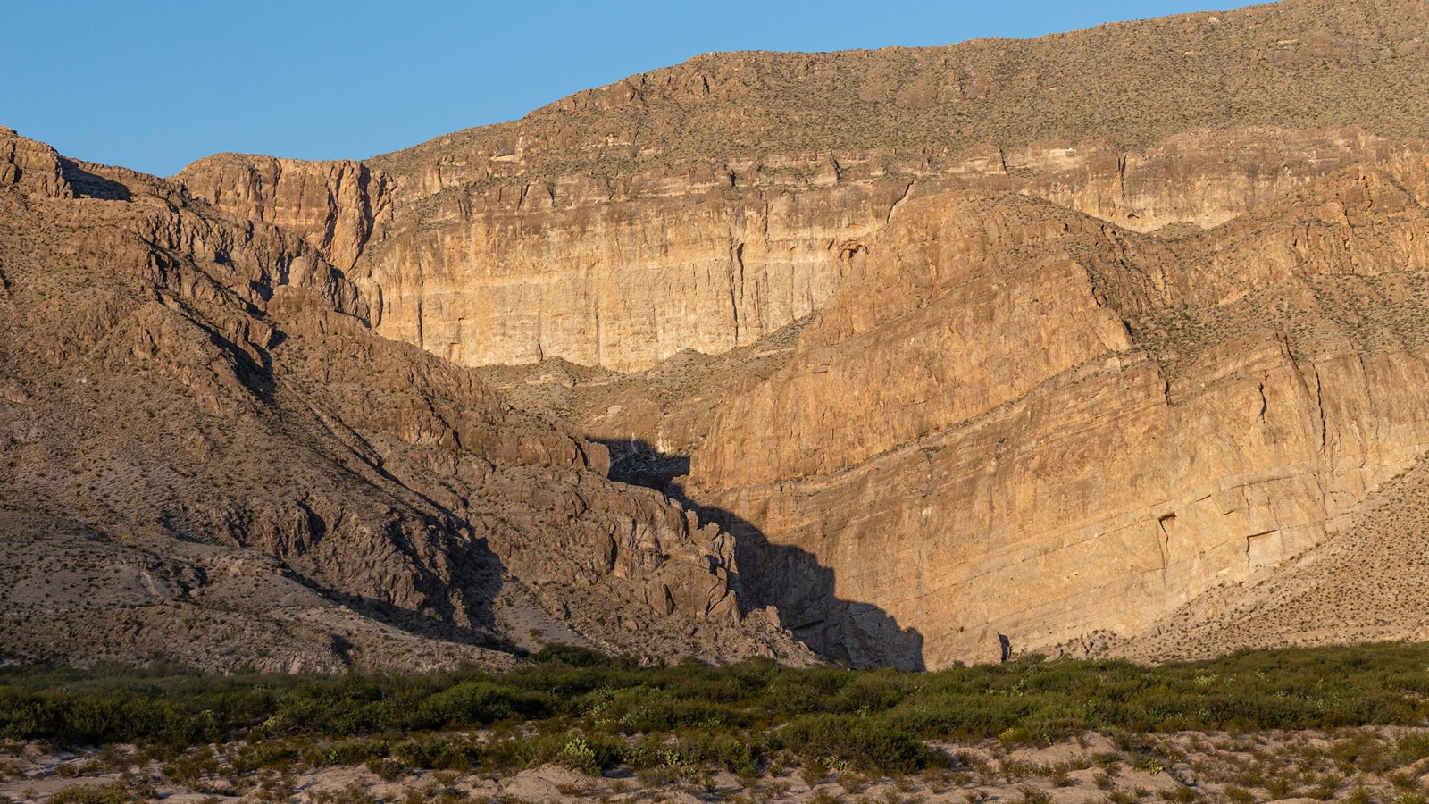 The Rio Grande flows through a large canyon that cuts the tall limestone cliffs.