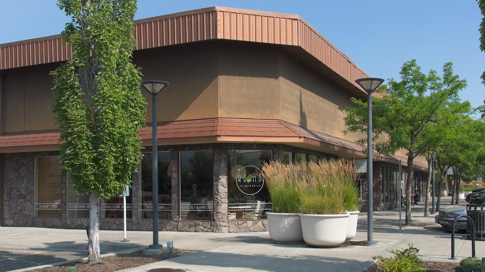 Corner of a brown two-story building with a line of trees on the right.