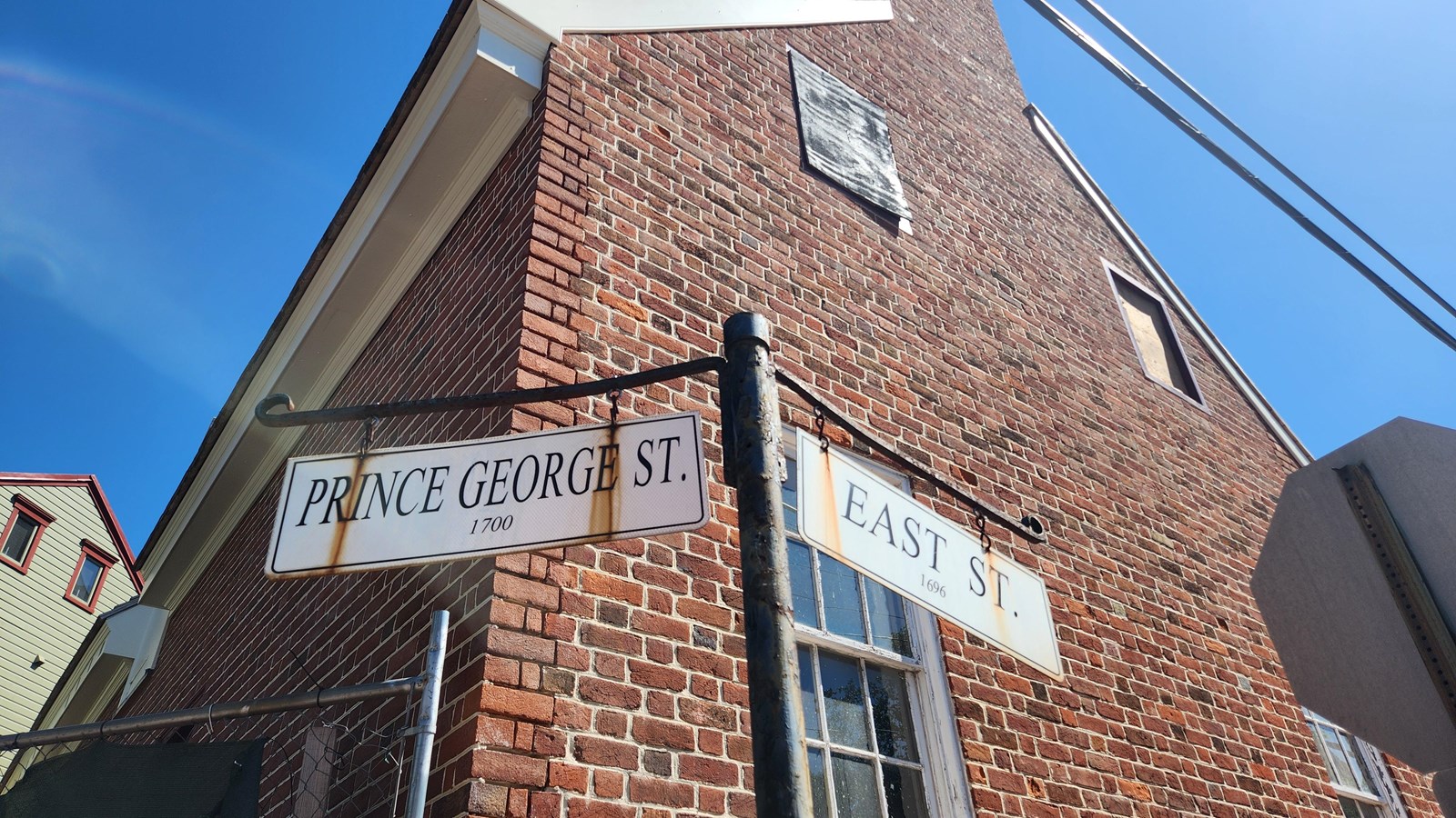 A street sign at the intersection features two white street signs hung from iron brackets.