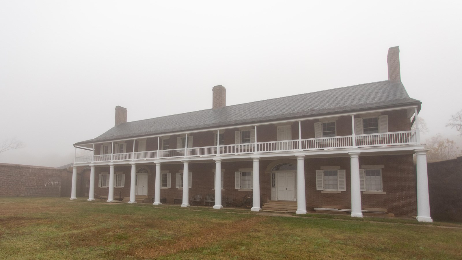 a two story brick house with white columns and a second story porch