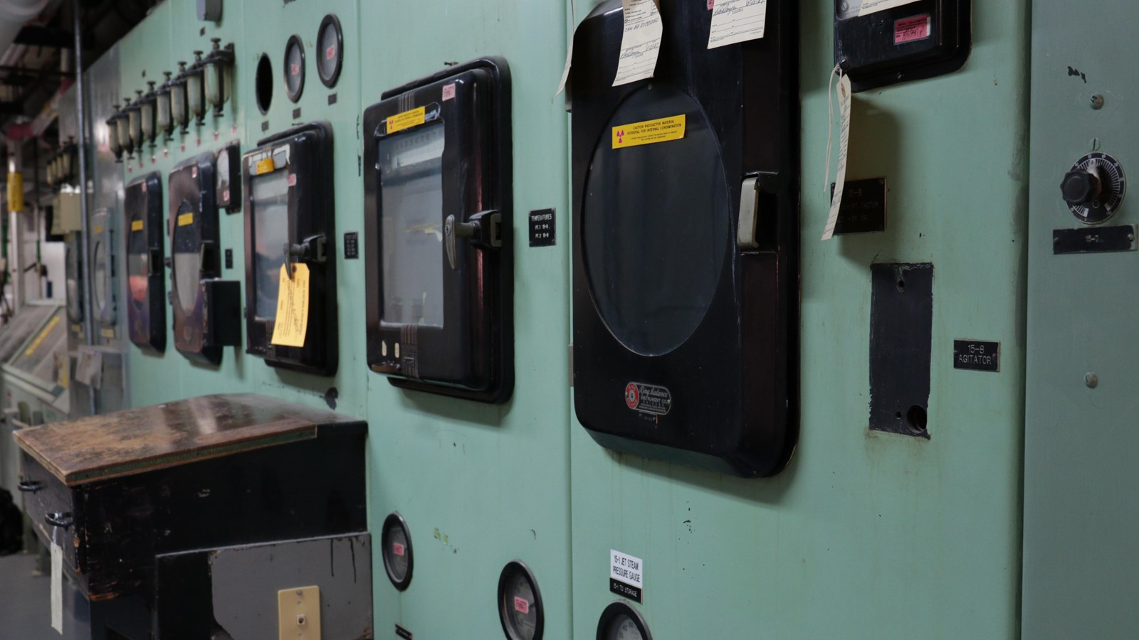 Color photograph of a large metal industrial panel with numerous dials and controls on it